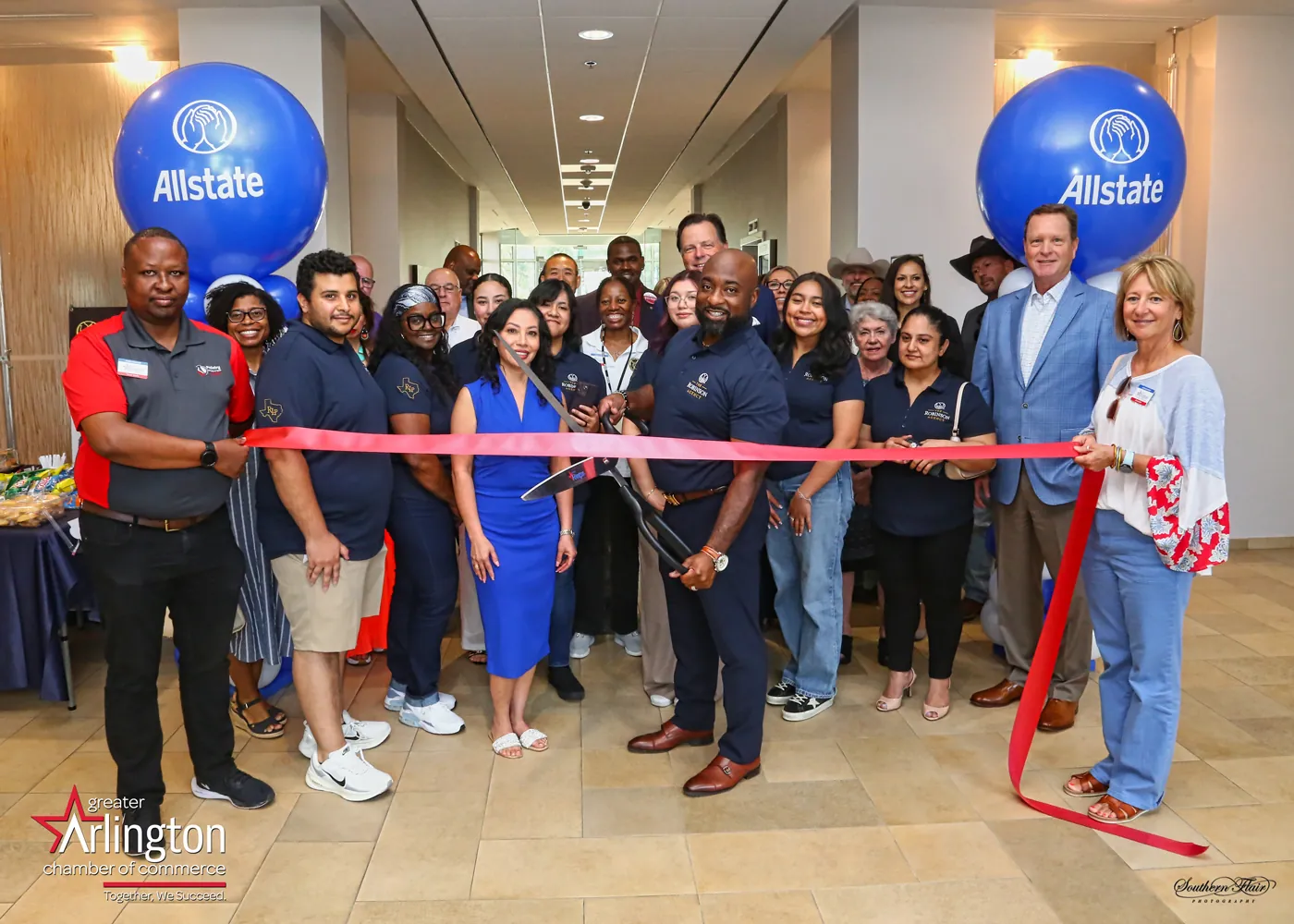Clarence Robinson II cutting the ribbon with his team and Greater Arlington Chamber of Commerce members at the agency's opening, June 3, 2026